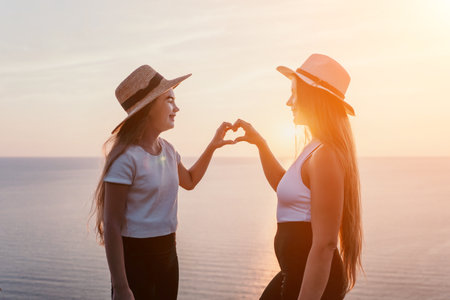 Mother and Daughter Making a Heart Shape at Sunsetの写真素材