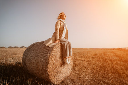 Woman Sitting on a Hay Bale in a Fieldの写真素材