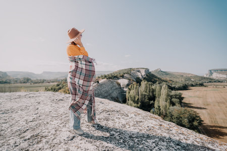 Woman in a Plaid Blanket Stands on a Cliff Topの写真素材