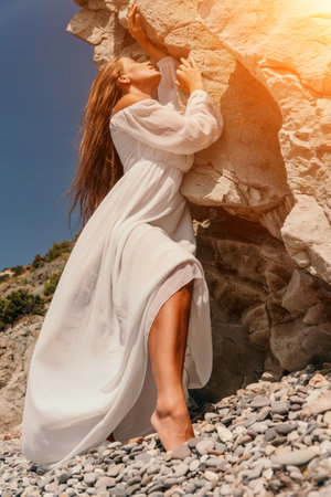 Woman, Dress, Rock: A woman in a white dress stands under a rock formation on a beach.の写真素材