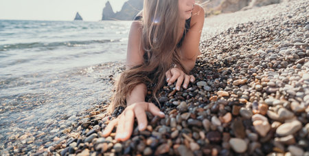 Woman on a Rocky Beach with the Ocean in the Backgroundの写真素材