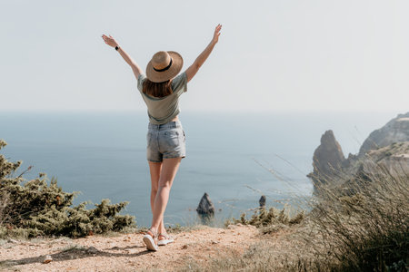 Woman in Hat on a Cliff Overlooking the Oceanの写真素材