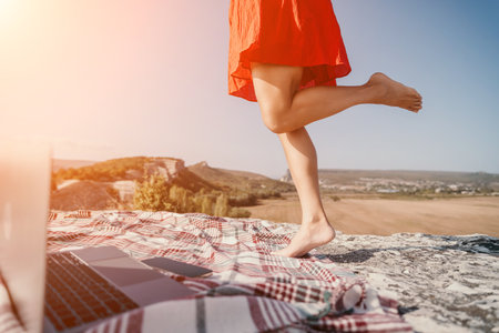 Woman in a Red Dress Stepping on a Blanket with a Laptopの写真素材