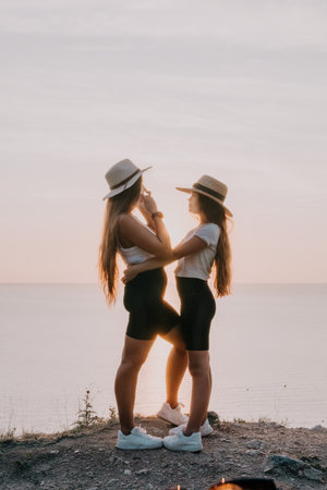 Two Young Women in Straw Hats Hugging by the Seaの写真素材