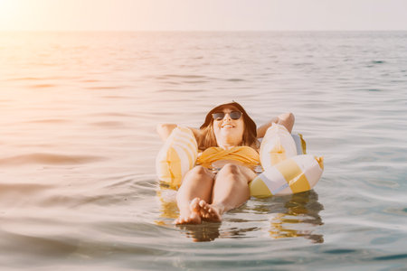 Woman, Inflatable Raft, Ocean - Relaxing on a colorful inflatable raft in the ocean on a sunny day.の写真素材