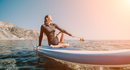 Woman Paddle Board Ocean - Female surfer sits on a paddle board in the ocean on a sunny day.の写真素材