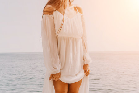 Woman White Dress Beach Sunset - A woman wearing a white dress stands on a beach at sunset.の写真素材