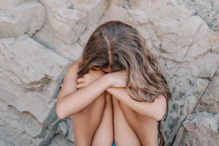 Portrait of a Young Girl Sitting Alone and Hiding Her Faceの写真素材