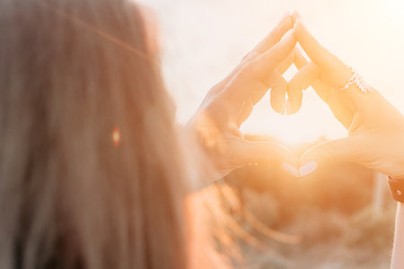 Hands Sun Meditation Woman meditating outdoors with hands forming triangle shape in front of sunset.
