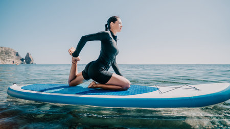 Yoga Paddleboard Woman Ocean - Young woman practices yoga on paddleboard in ocean.の写真素材