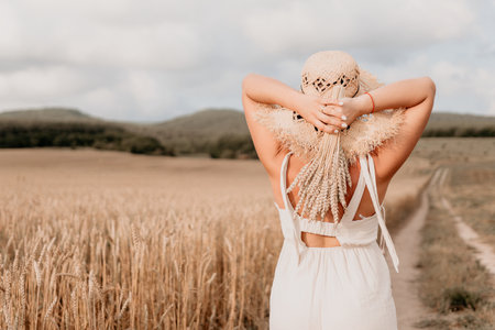 Woman in a White Dress and Straw Hat in a Wheat Fieldの写真素材