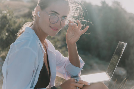 Woman, Laptop, Beach: A smiling woman sits on a beach with a laptop.の写真素材
