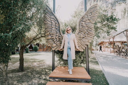 Woman Posing with Angel Wings Sculpture in a Gardenの写真素材