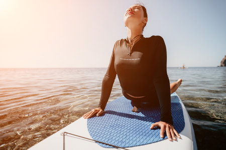 Yoga Paddleboard Water Sport Woman Stretching on Paddleboard at Seaの写真素材