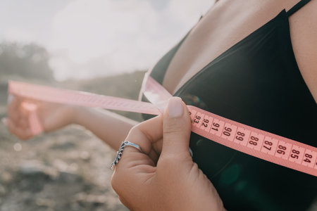 Measuring Tape, Bra, Woman: Close-up of a woman using a measuring tape to measure her bra size.の写真素材