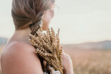 Woman Holding Wheat in a Field at Sunsetの写真素材