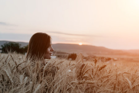 Woman Wheat Field Sunset: Serene contemplation amidst golden harvest at dusk.の写真素材