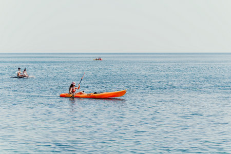 Kayaking Ocean Water Sports - Two people kayaking on a calm ocean with other kayakers in the distance.の写真素材