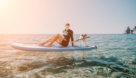 Woman Dog Paddleboard Ocean - Woman sits on a paddleboard with her dog in the ocean on a sunny day.の写真素材
