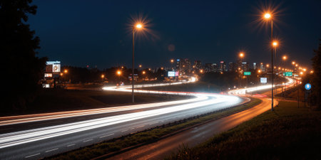 A panoramic view of a busy highway interchange at night, with streaks of car headlights and taillights creating dynamic patterns of light againstの素材