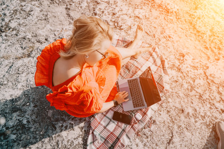 Woman Working on a Laptop in a Scenic Outdoor Settingの写真素材