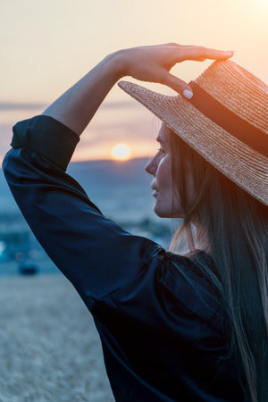 Woman Sunset Hat: Outdoor portrait, serene sunset landscape, summer evening, peaceful contemplation.の写真素材