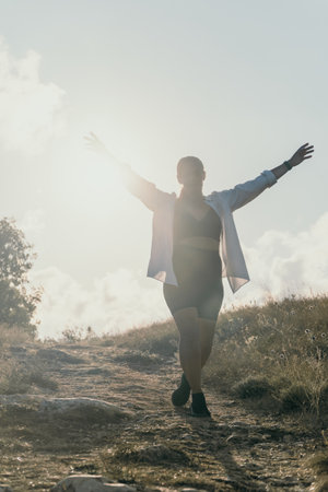 Woman Hiking Mountain Sunlight - A woman walks across a rocky mountain path with her arms outstretched towards the sun.の写真素材