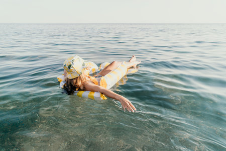 Woman, Float, Ocean: A woman relaxes on an inflatable float in the sea.の写真素材
