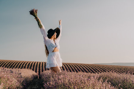 Woman in a White Dress and Hat Posing in Lavender Fieldの写真素材