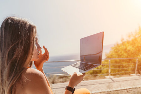 Woman Using Laptop Outdoors on a Sunny Dayの写真素材