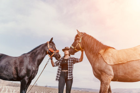 Woman Horses Ranch - A woman in a cowboy hat standing with two horses on a ranch.の写真素材