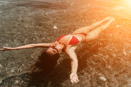 Woman Red Bikini Floating Sunlit Waterの写真素材