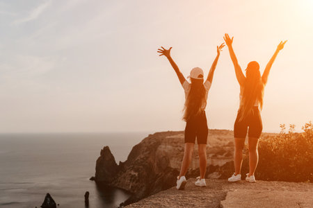 Two Women Celebrating on a Cliff Overlooking the Seaの写真素材