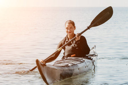 Woman sea kayak. Happy smiling woman in kayak on ocean, paddling with wooden oar. Calm sea water and horizon in background. Active lifestyle at sea. Summer vacation.の写真素材