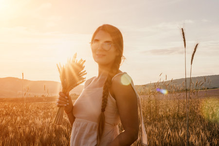 Woman wheat field. Agronomist, Woman farmer check golden ripe barley spikes in cultivated field. A woman is holding a bunch of wheat in her arms.の写真素材