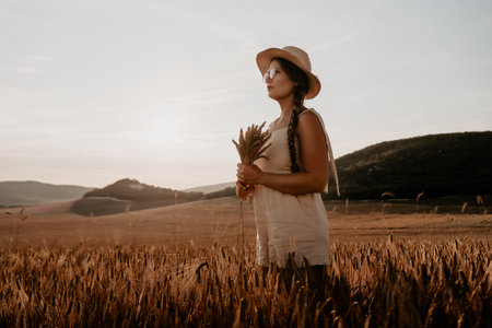 Woman in Straw Hat and White Dress Standing in a Fieldの写真素材