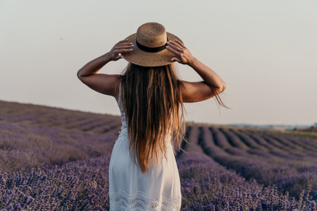 Lavender Fields Woman Hat France: Summer travel photography showcasing a woman in a white dress and straw hat admiring a vast lavender field in Provence, France.の写真素材