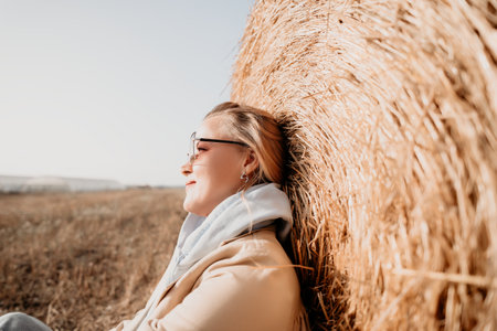 Woman Relaxing Against a Hay Bale in a Fieldの写真素材