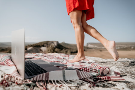 Laptop and Blanket on a Cliff with a Woman Walking Awayの写真素材