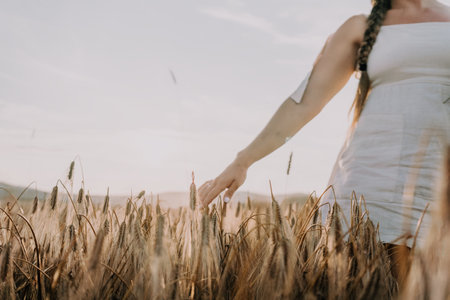 Woman in White Dress Runs Through Golden Wheat Fieldの写真素材