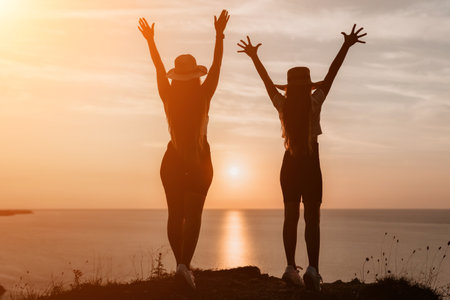 Silhouettes of Two Women on a Cliff at Sunsetの写真素材