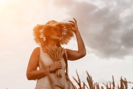 Woman wheat field. Agronomist, Woman farmer check golden ripe barley spikes in cultivated field. A woman is holding a bunch of wheat in her arms.の写真素材