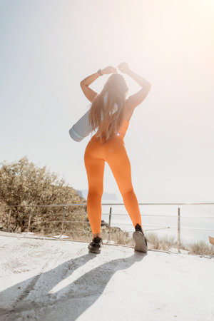 Woman in Orange Outfit Standing with Yoga Matの写真素材