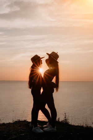 Silhouettes of Two Women in Hats at Sunsetの写真素材