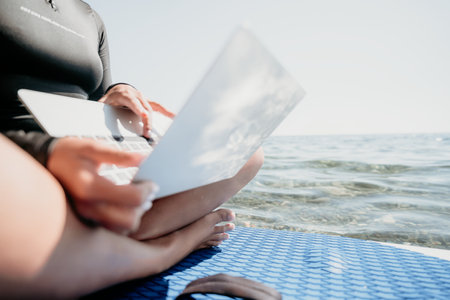 Laptop, Beach, Work - Woman working on laptop while sitting on a beach.の写真素材