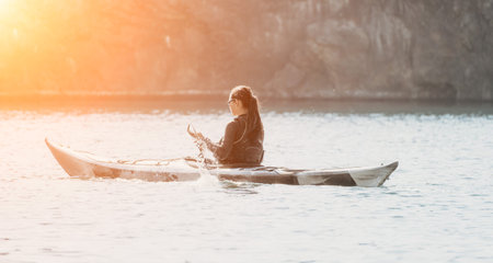 Kayaking Woman Sunset Lake - A lone woman paddles a kayak on a lake at sunset, enjoying the peaceful...