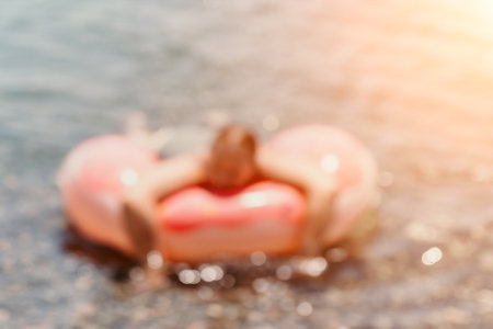 Inflatable, Beach, Summer: Person Relaxing on an Inflatable Ring in Water at Sunset. (99 characters)の写真素材