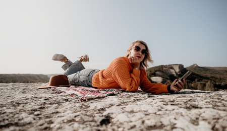 Woman Relaxing on a Mountaintop with a Smartphone