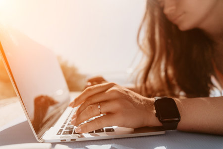 Woman Typing on Laptop with Sunlightの写真素材
