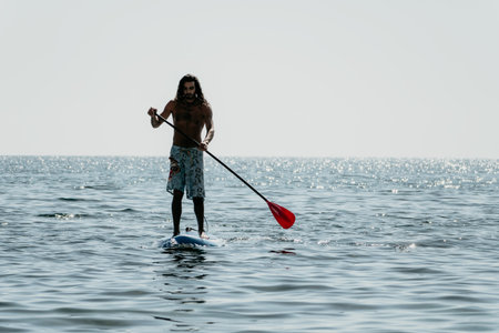 Man Paddleboarding Ocean Water Sport - Silhouette of a man paddleboarding on the ocean.の写真素材
